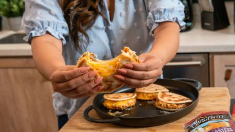Woman holding open gordita filled with chorizo, beans, and cheese
